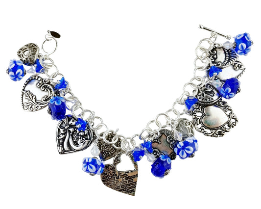 Charmed bracelet with blue beads and silver heart-shaped charms on a white background