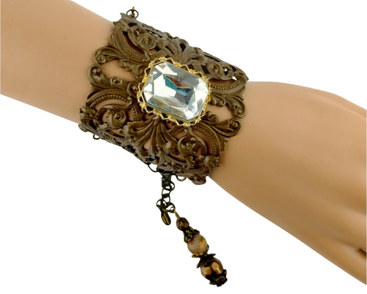 Decorative bracelet with a large gemstone on a mannequin wrist against a white background
