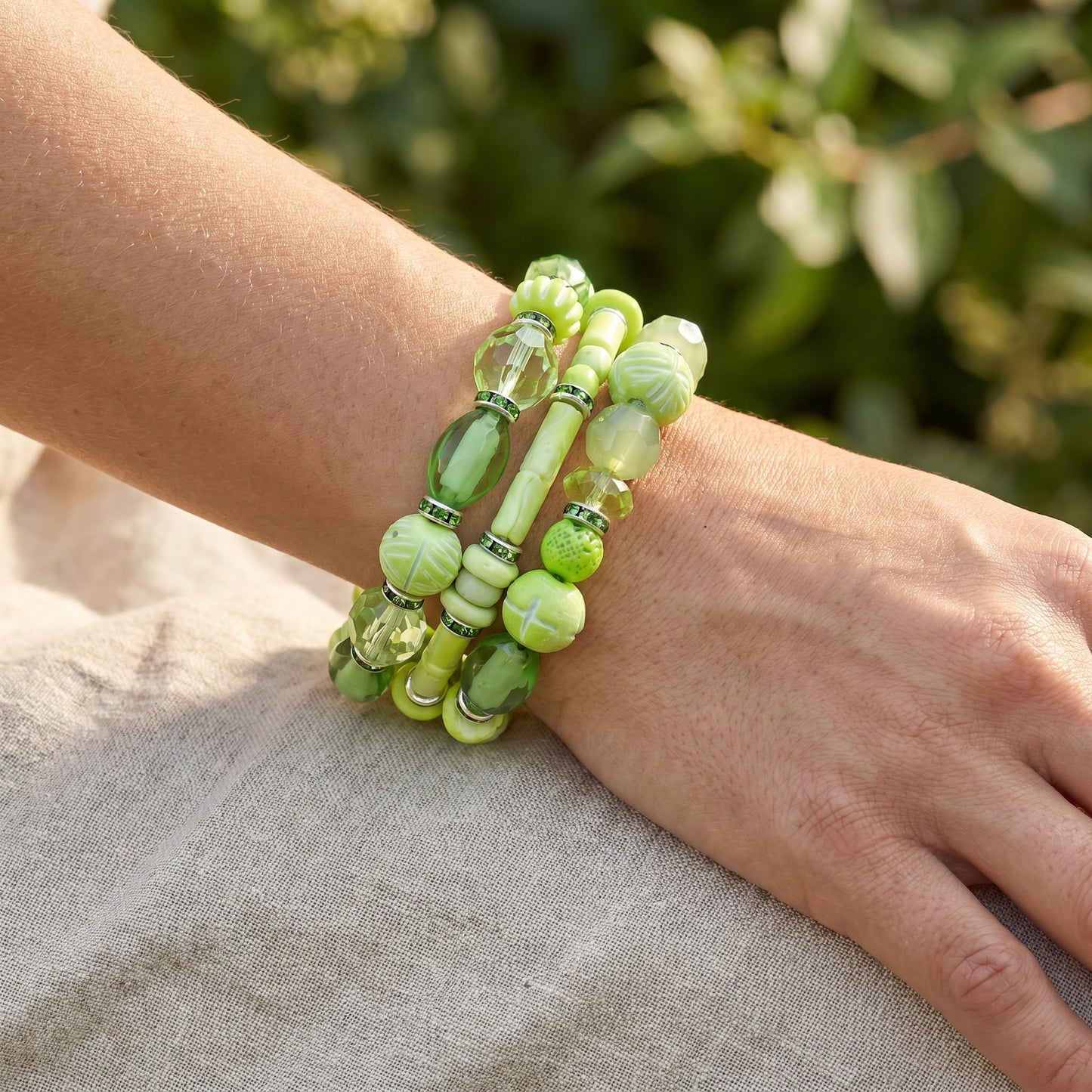 Green beaded bracelet on a wrist with a blurred green background