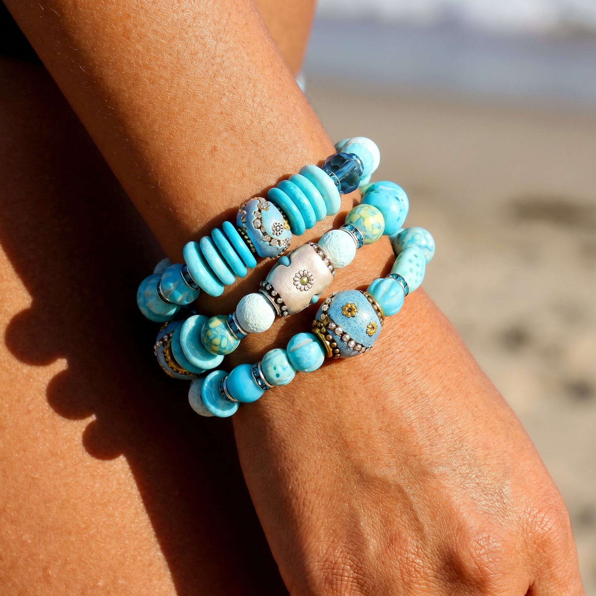 Turquoise beaded bracelets on a wrist with a beach background
