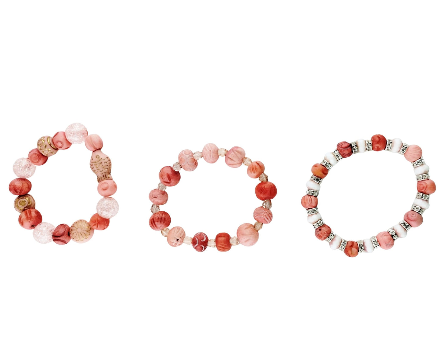 Three beaded stretch bracelets arranged side by side on a plain white background. The bracelets feature round beads in shades of pink, coral, terracotta, and white, with some silver-toned spacer accents.
