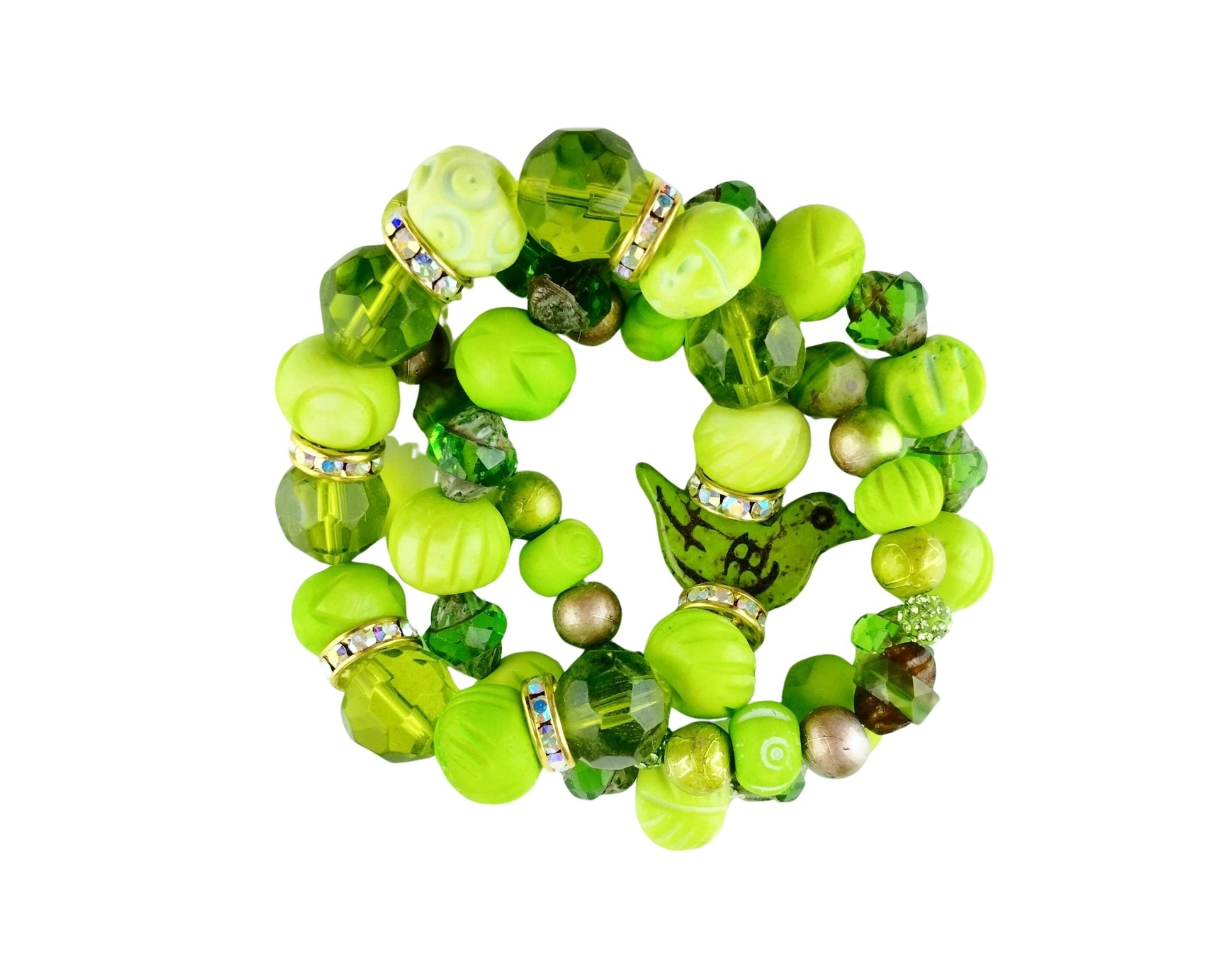 A set of three overlapping beaded stretch bracelets in various shades of green, featuring faceted beads, textured round beads, clear rhinestone spacers, and a small green bird charm, displayed on a solid white background.
