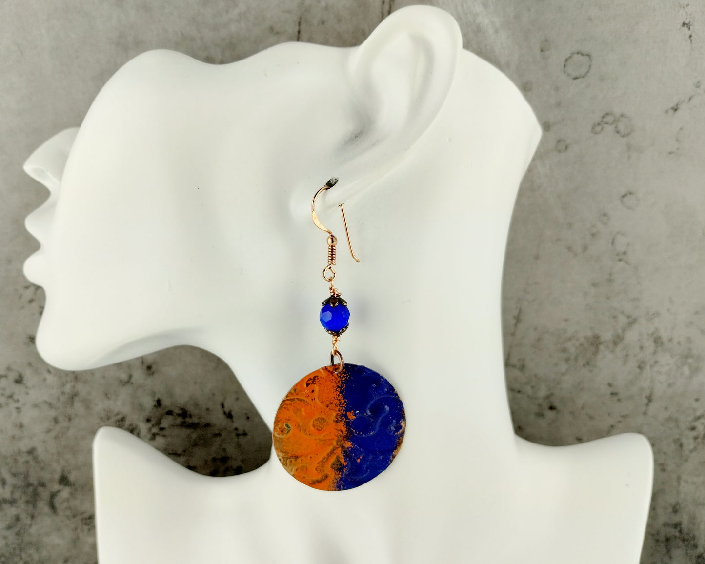 Hand-painted navy and orange copper earrings on display