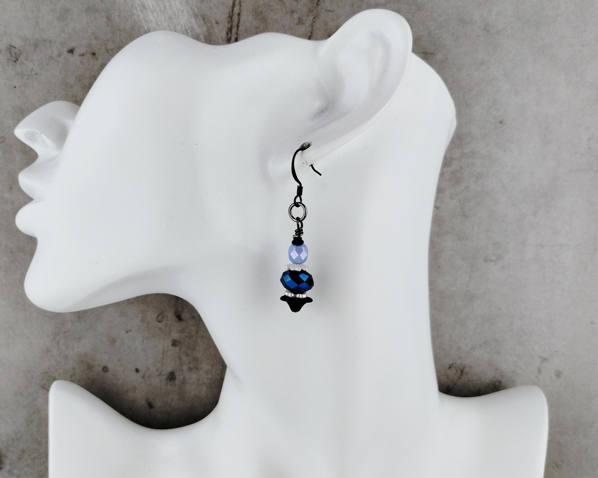 Earring displayed on a white mannequin ear with a gray background