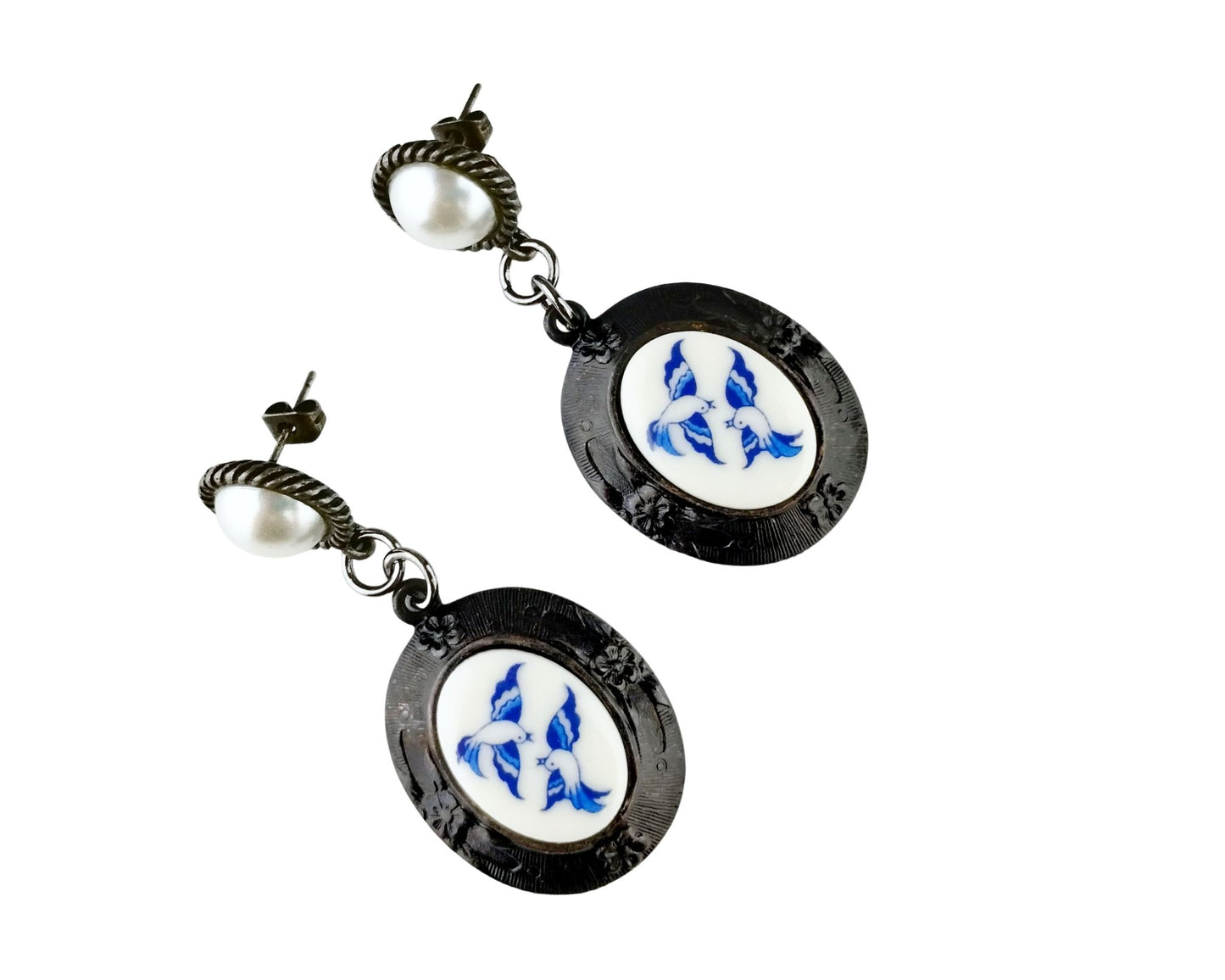 Pair of earrings with black circular designs featuring blue and white patterns on a white background.