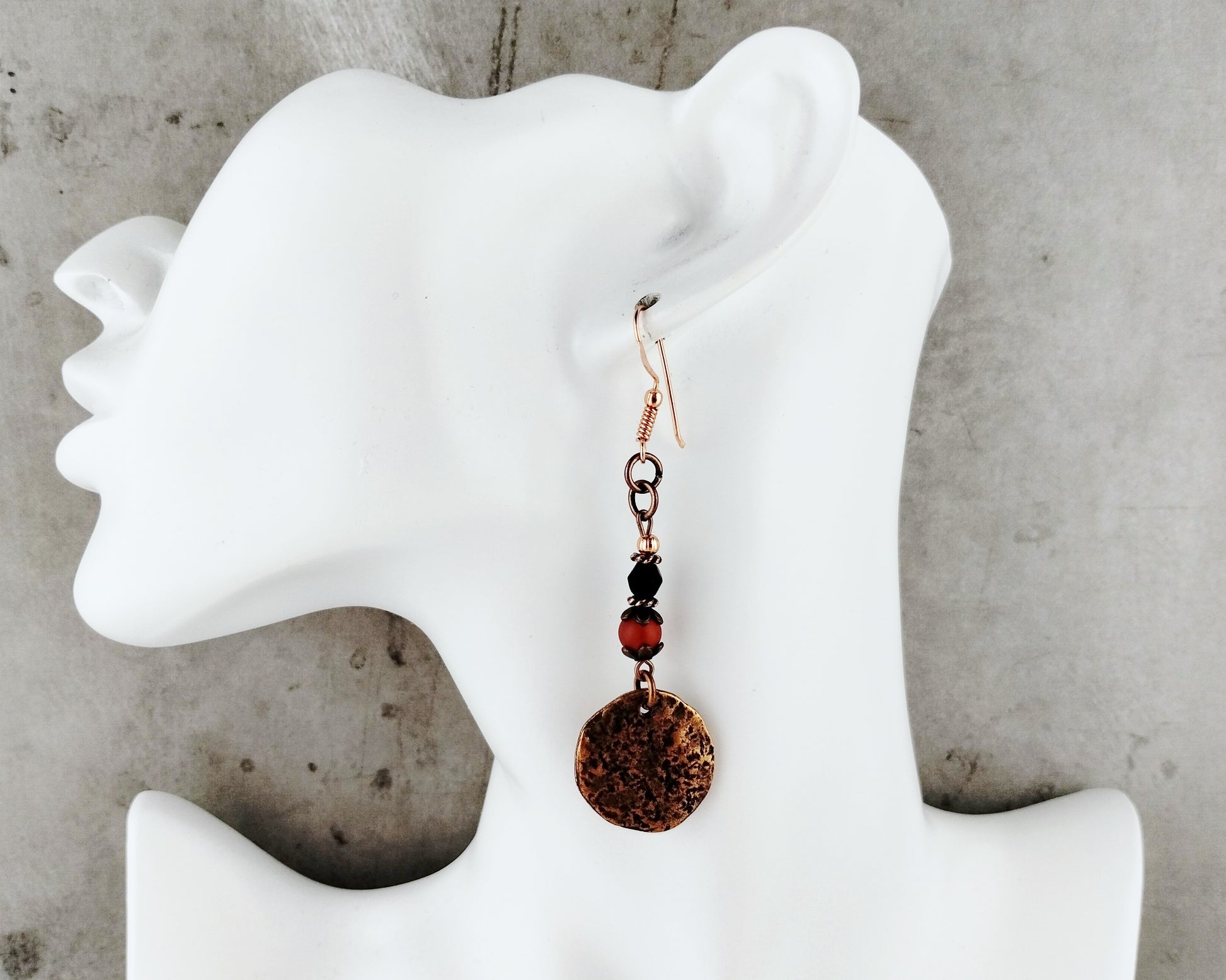 Earring on a white mannequin ear with a concrete background
