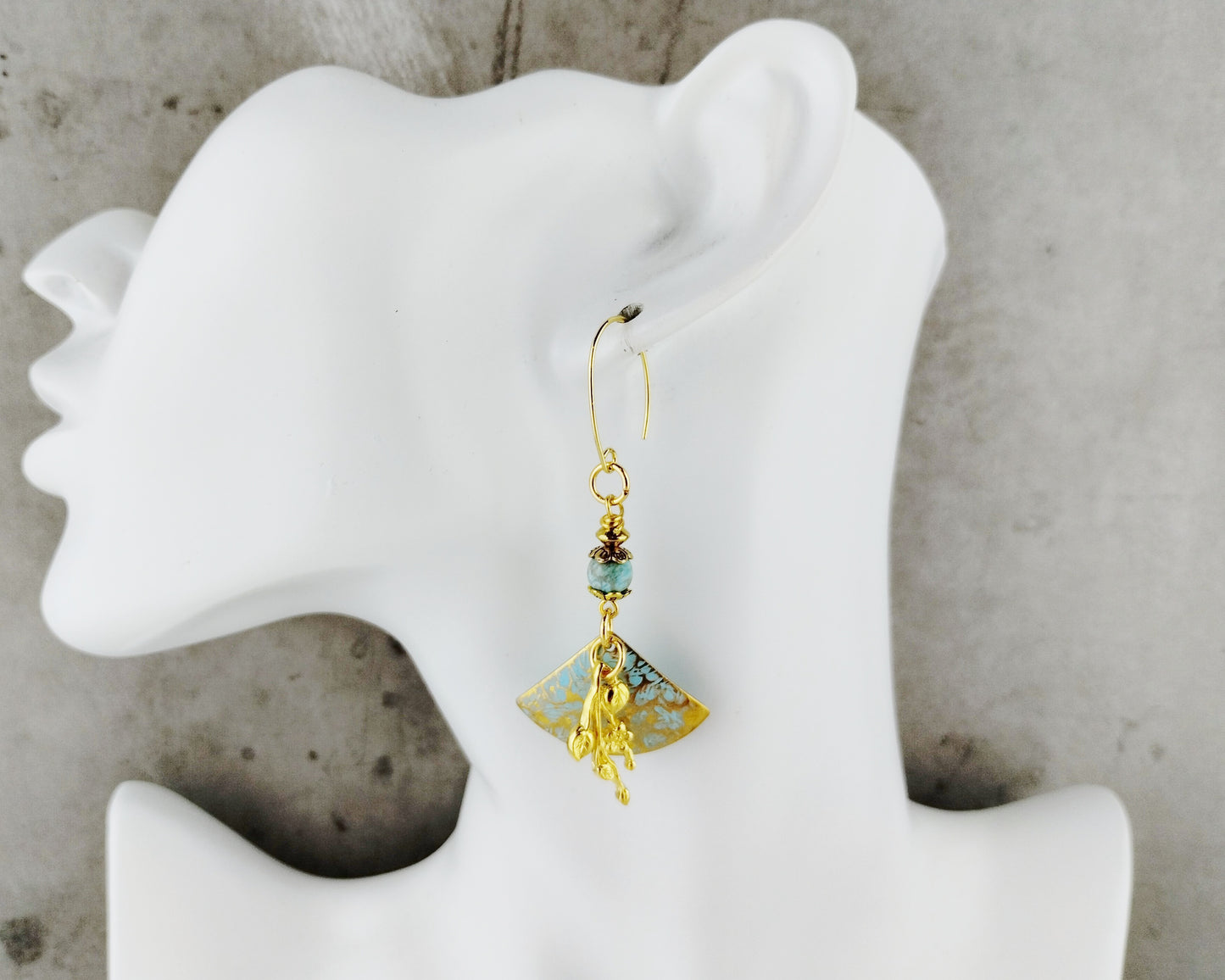 Gold and turquoise beaded earring on a white mannequin ear