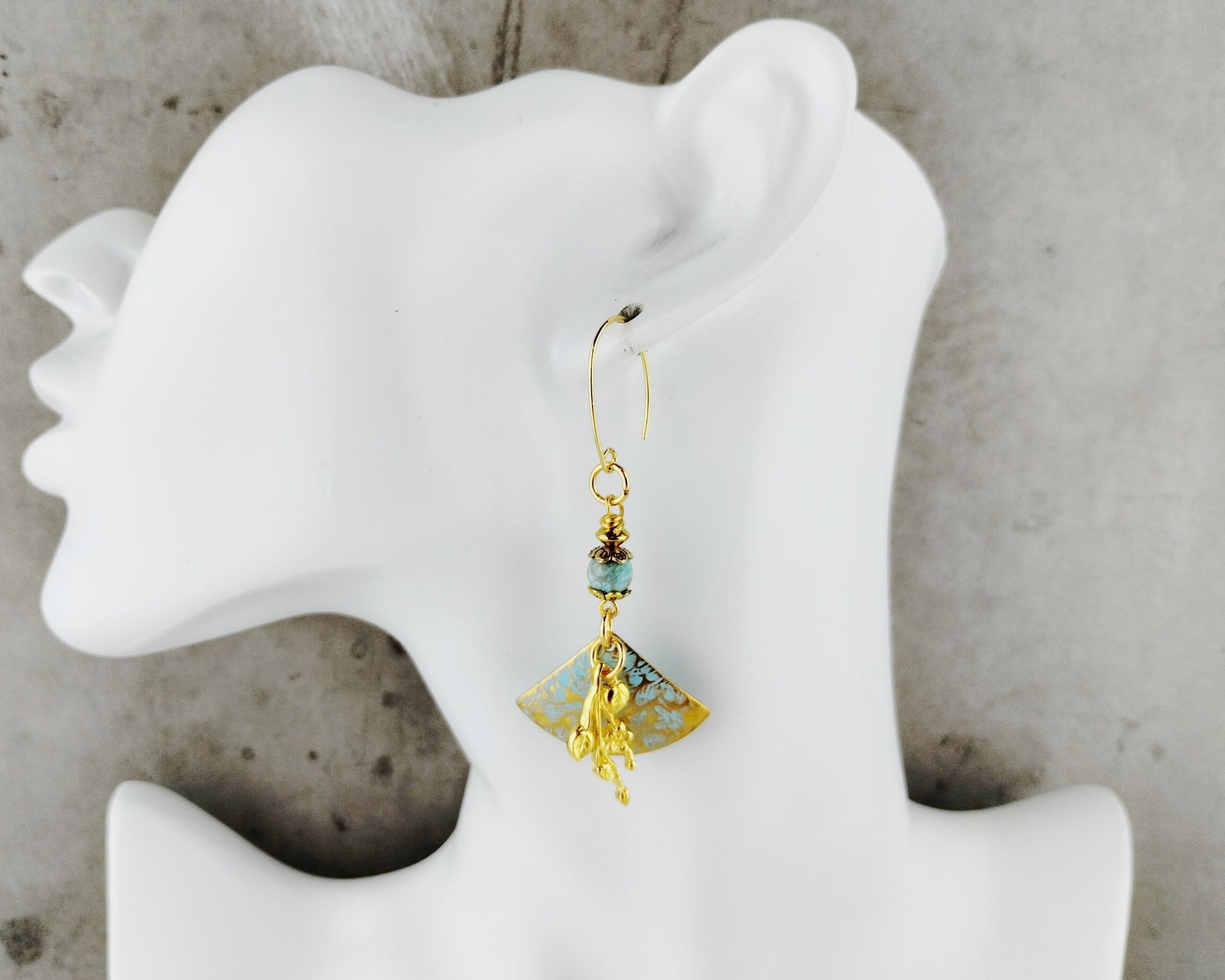 Gold and turquoise beaded earring on a white mannequin ear