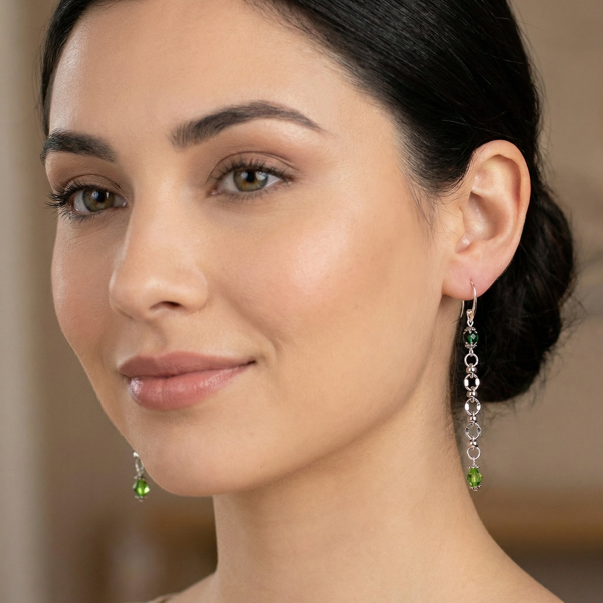 Close-up of a woman wearing green drop earrings with a blurred background