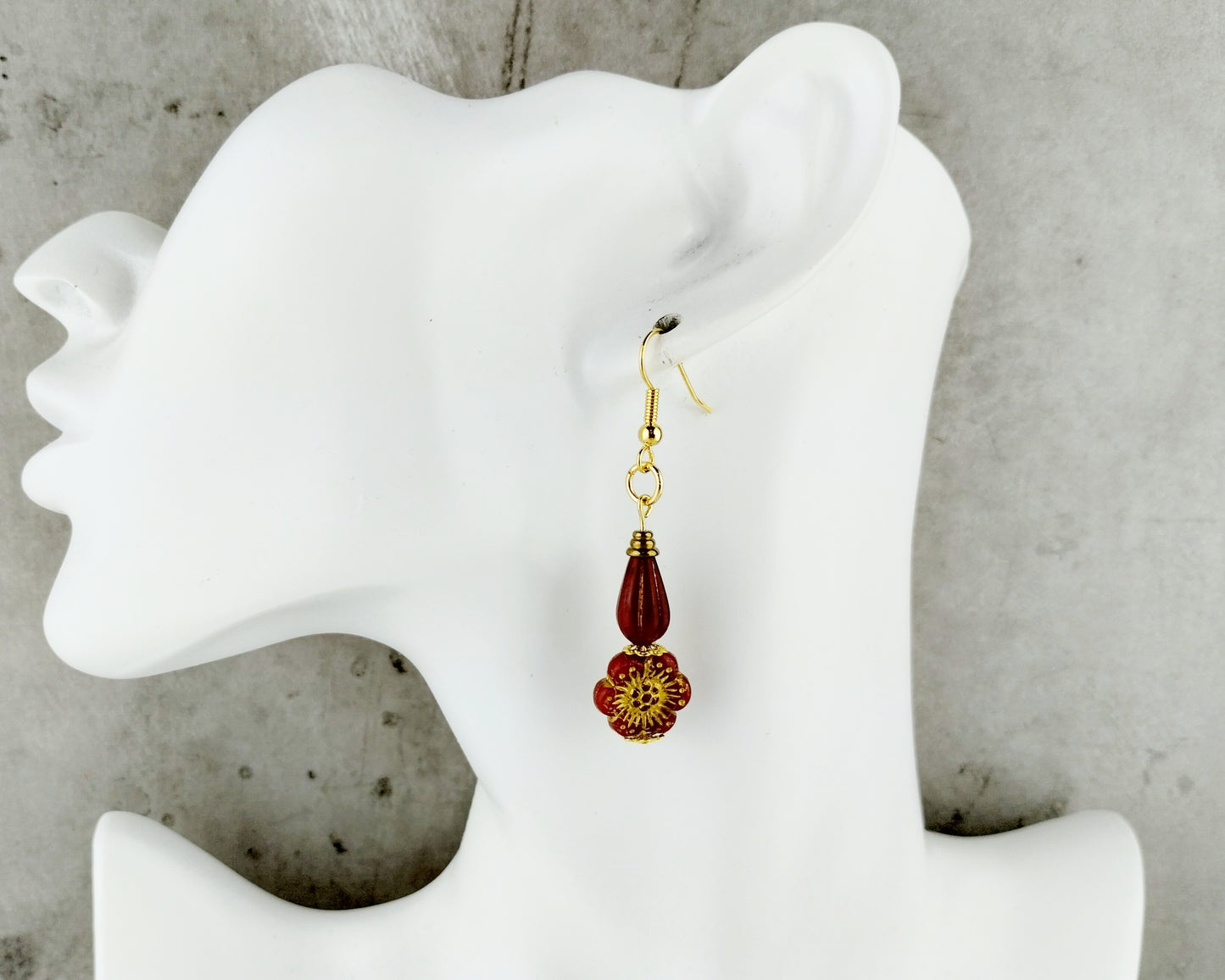 Red Earrings with a floral design on a white mannequin ear