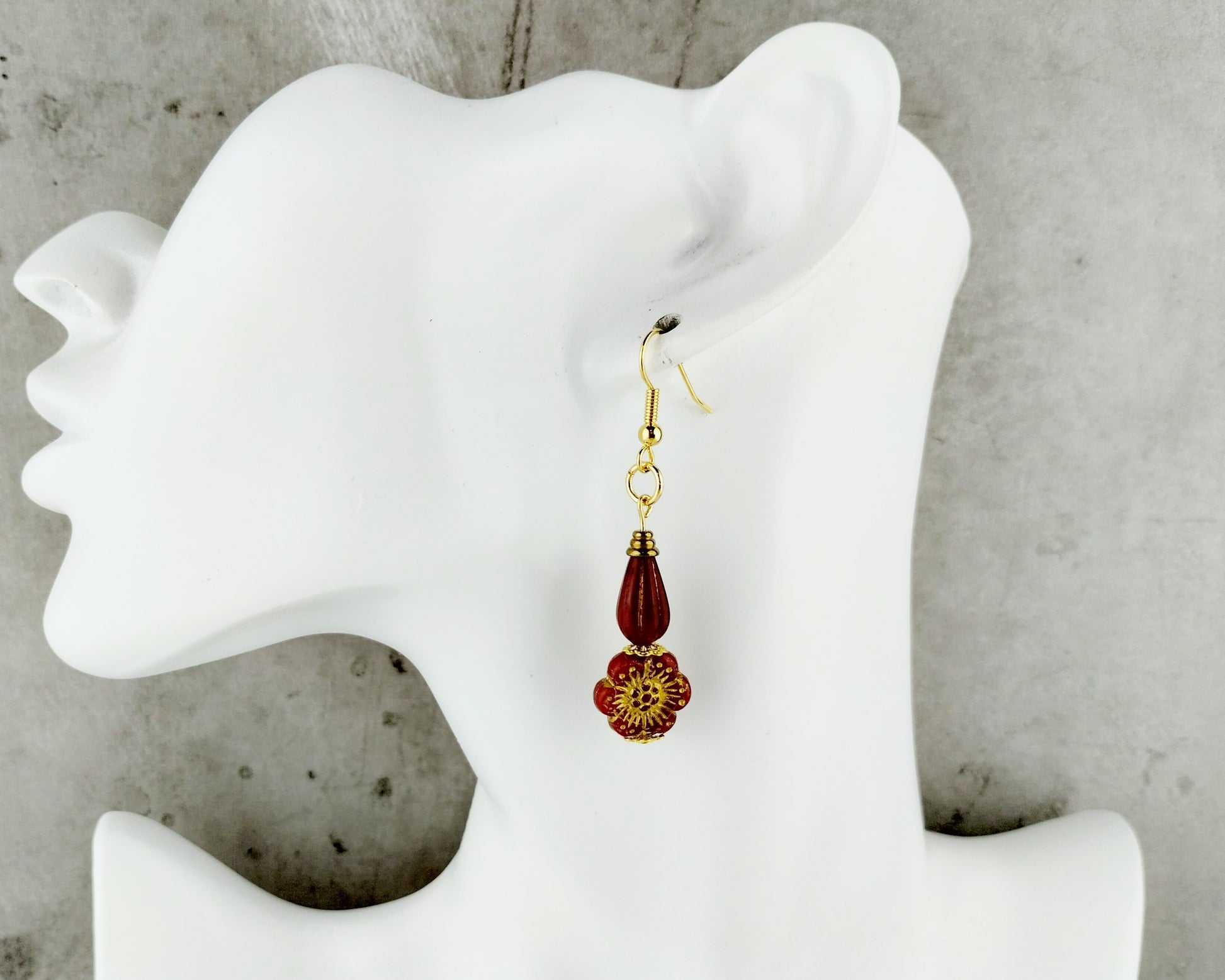 Red Earrings with a floral design on a white mannequin ear