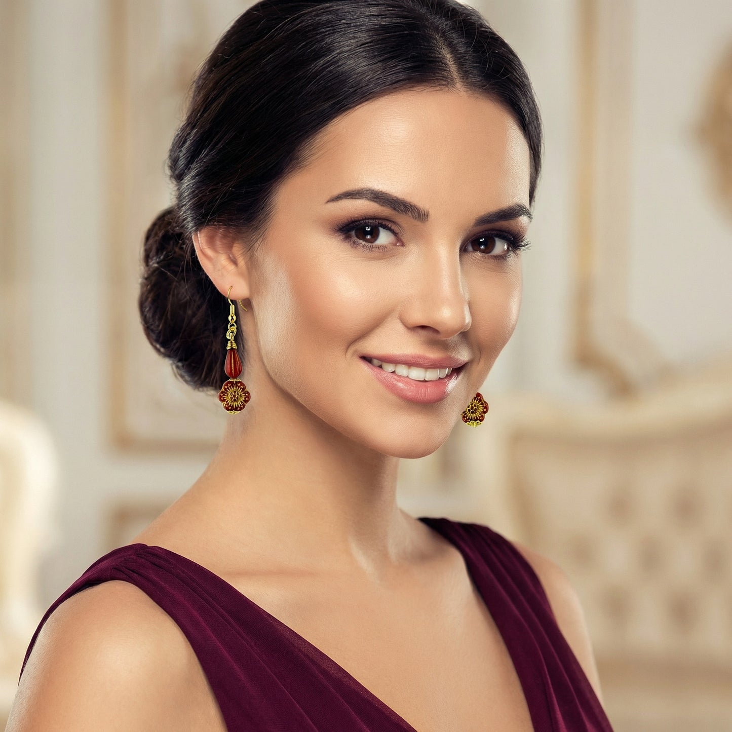 Woman wearing red earrings with gold accents  in a blurred indoor setting