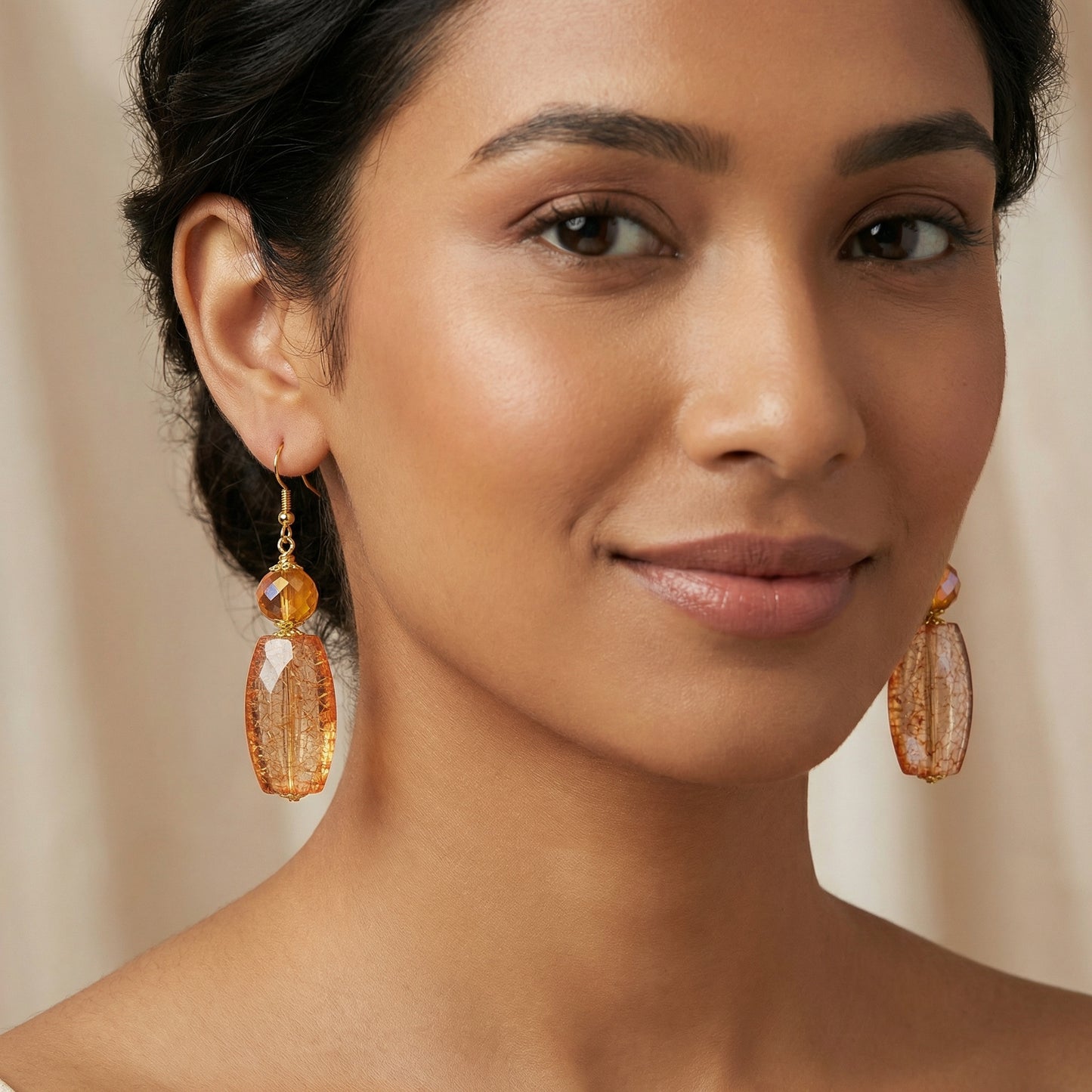 Woman wearing orange earrings with a neutral background