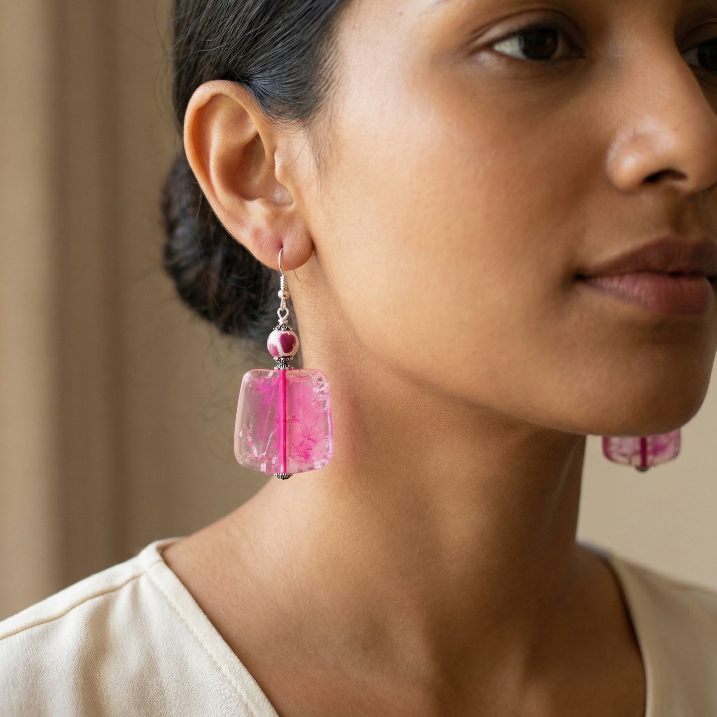 Close-up of a woman wearing pink earrings with a neutral background