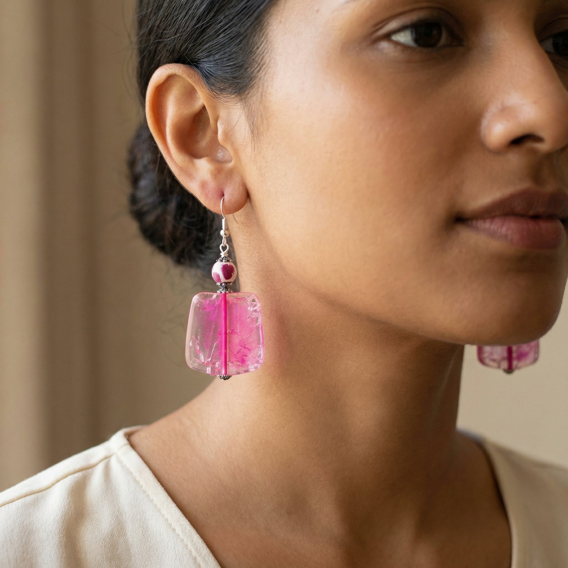 Close-up of a woman wearing pink earrings with a neutral background