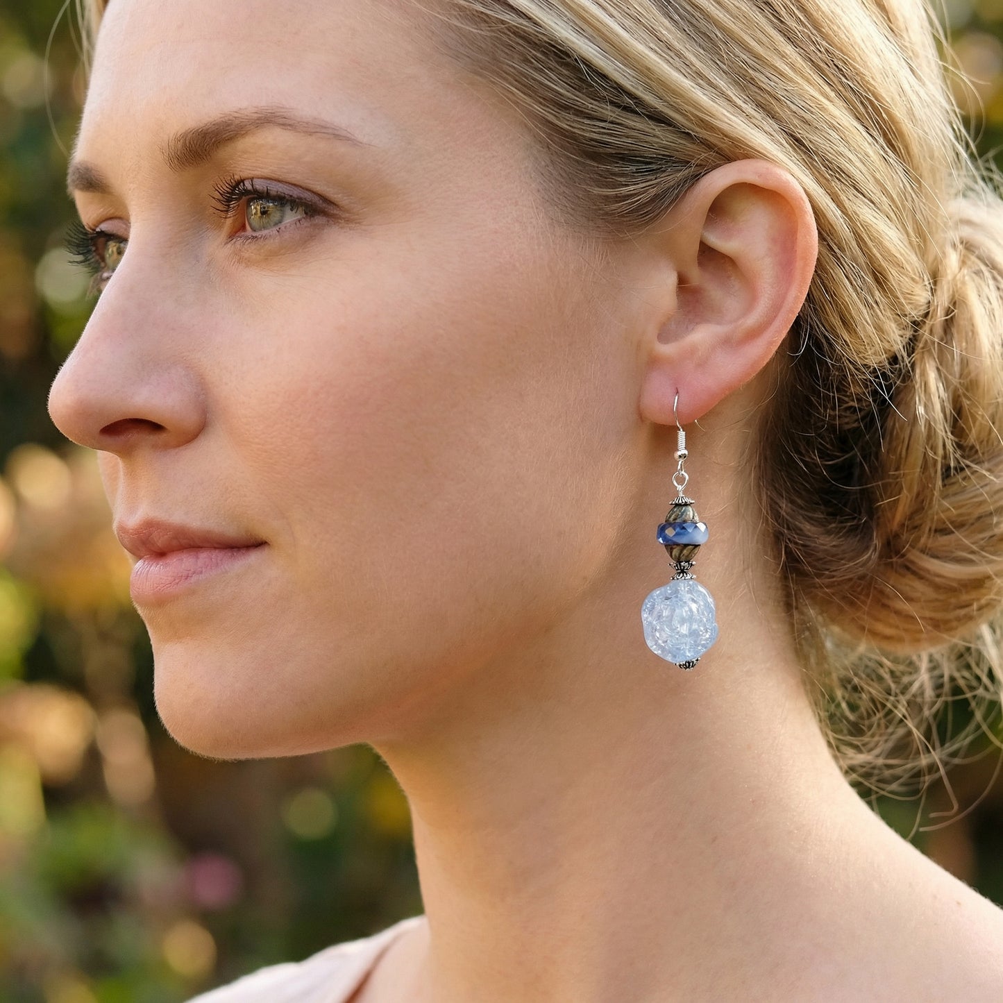 Close-up of a woman wearing a silver earring with a blue beads outdoors.