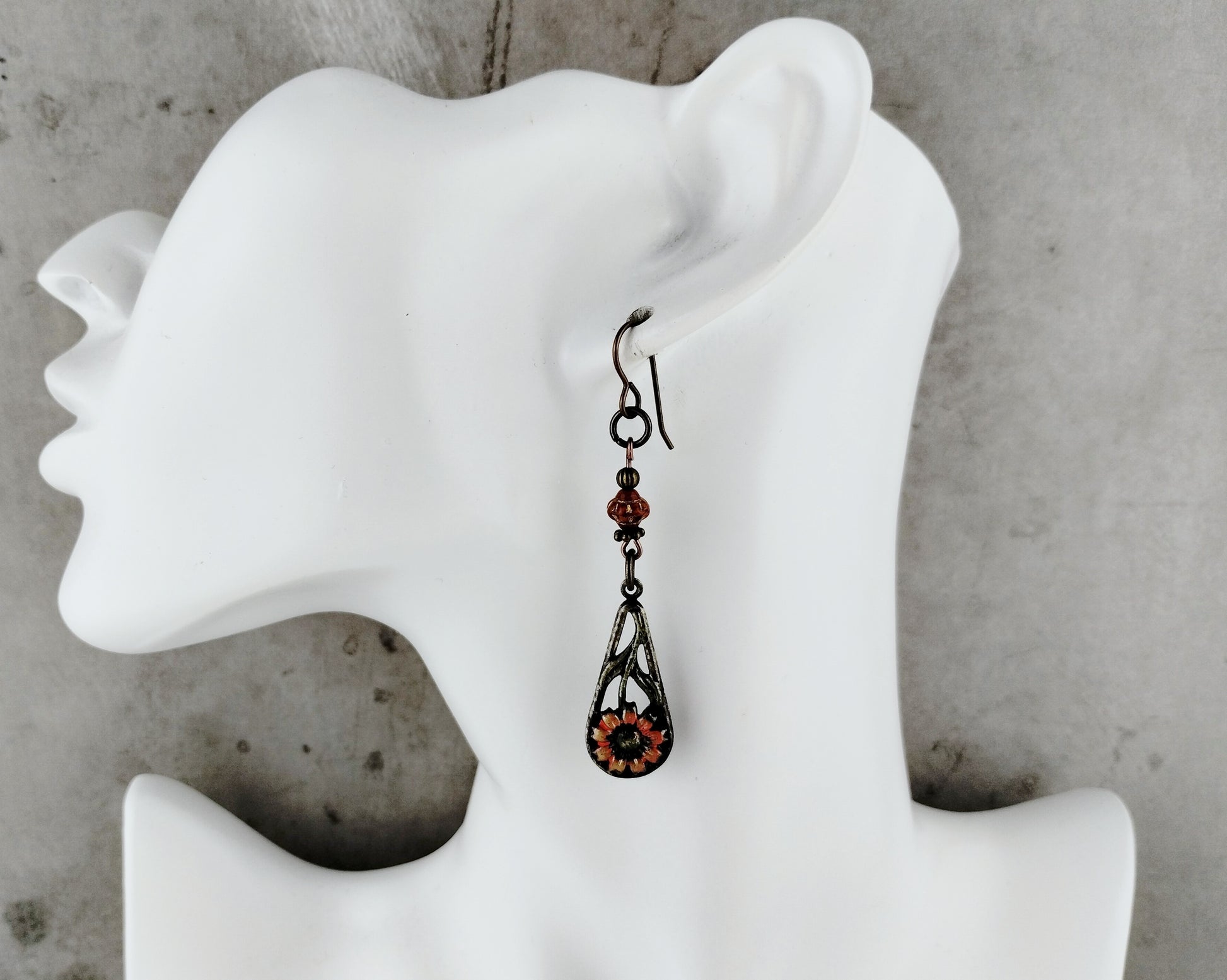 Earring displayed on a white mannequin ear against a gray background