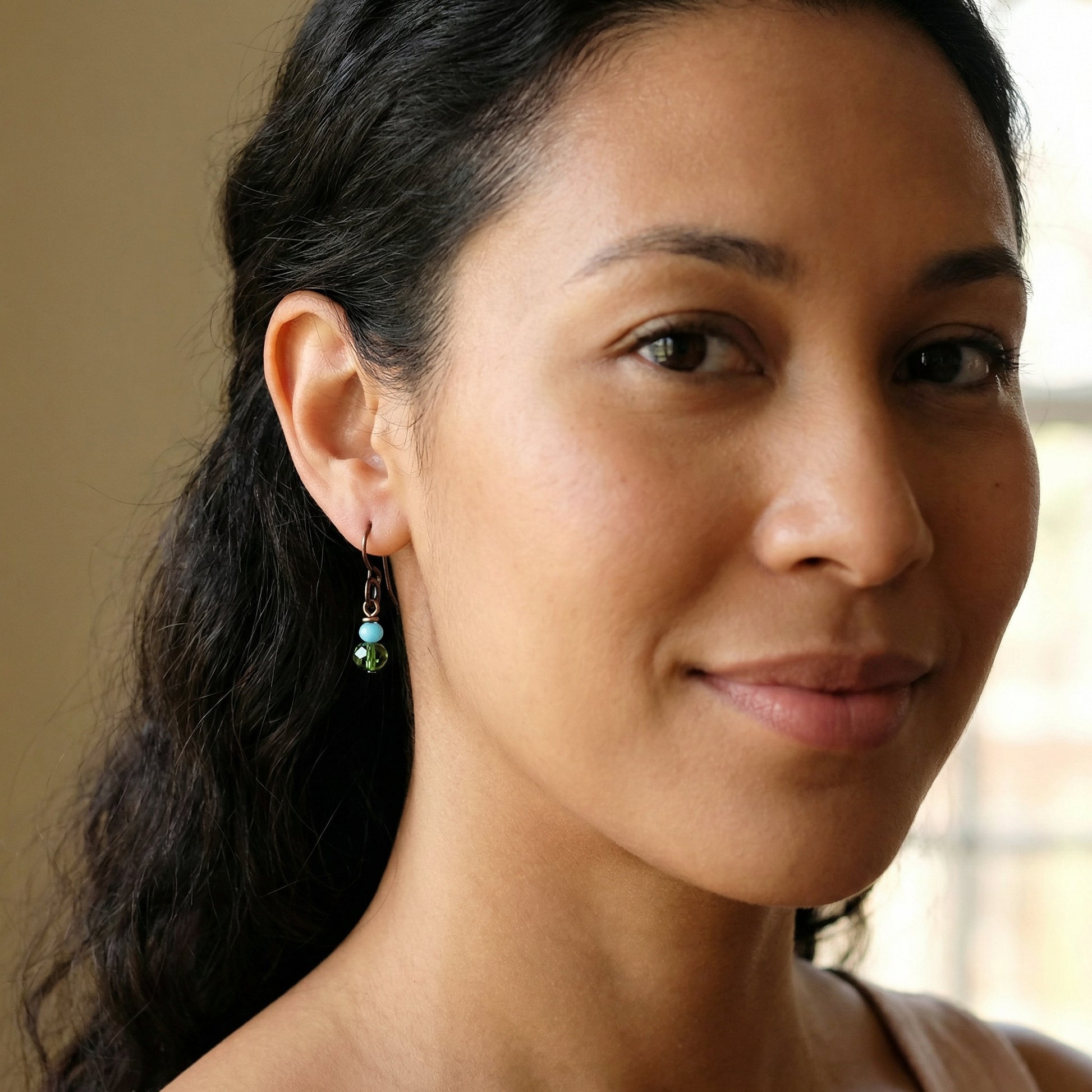 Close-up of a woman with dark hair and earrings, blurred background