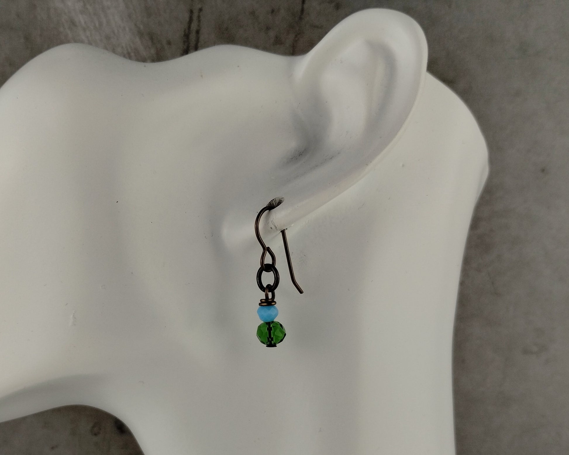 Earring with green and blue beads on a mannequin ear