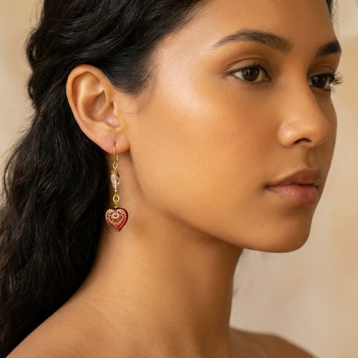 Close-up of a woman wearing heart-shaped earrings with a neutral background