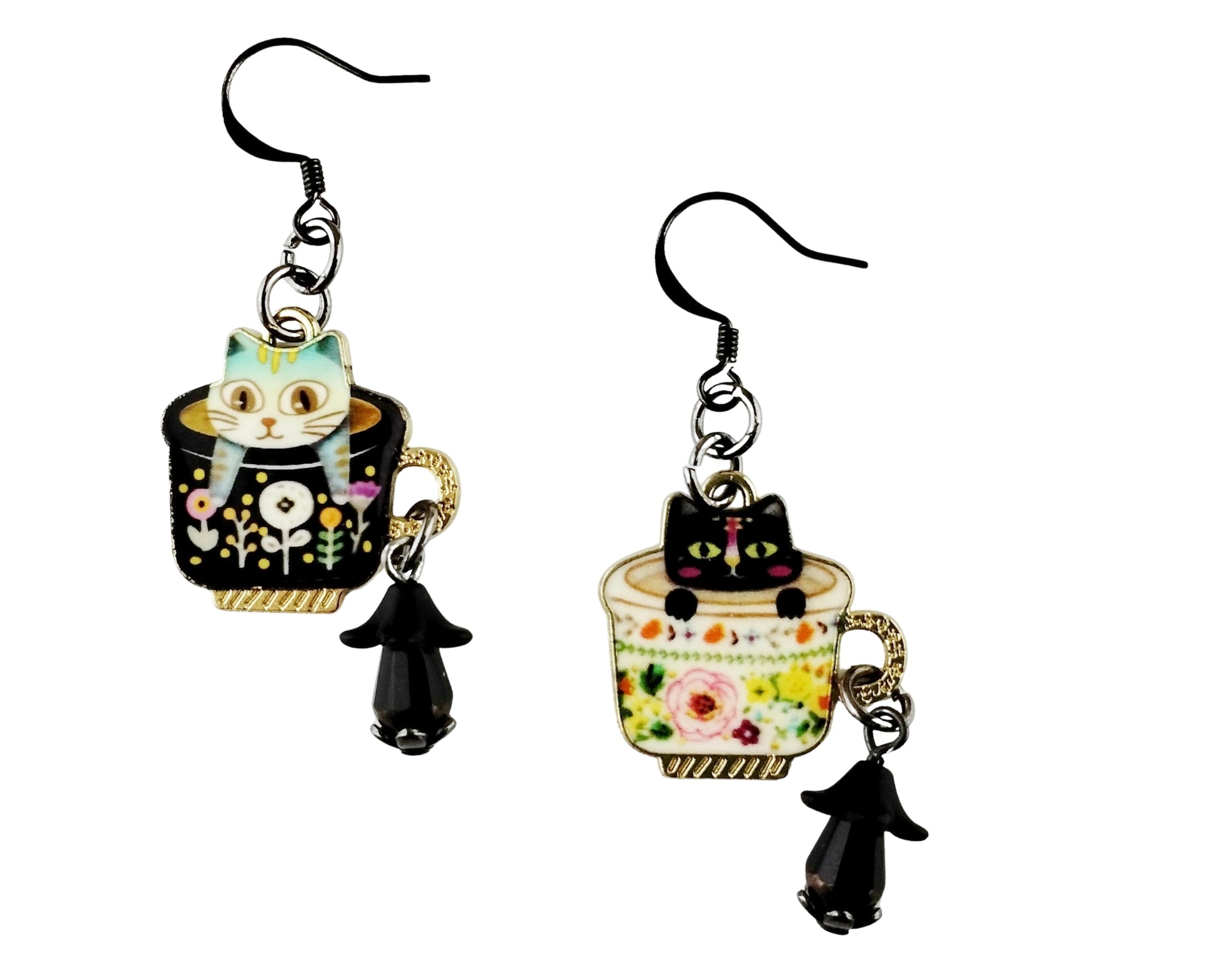 Pair of earrings with cat and tea cup designs on a white background