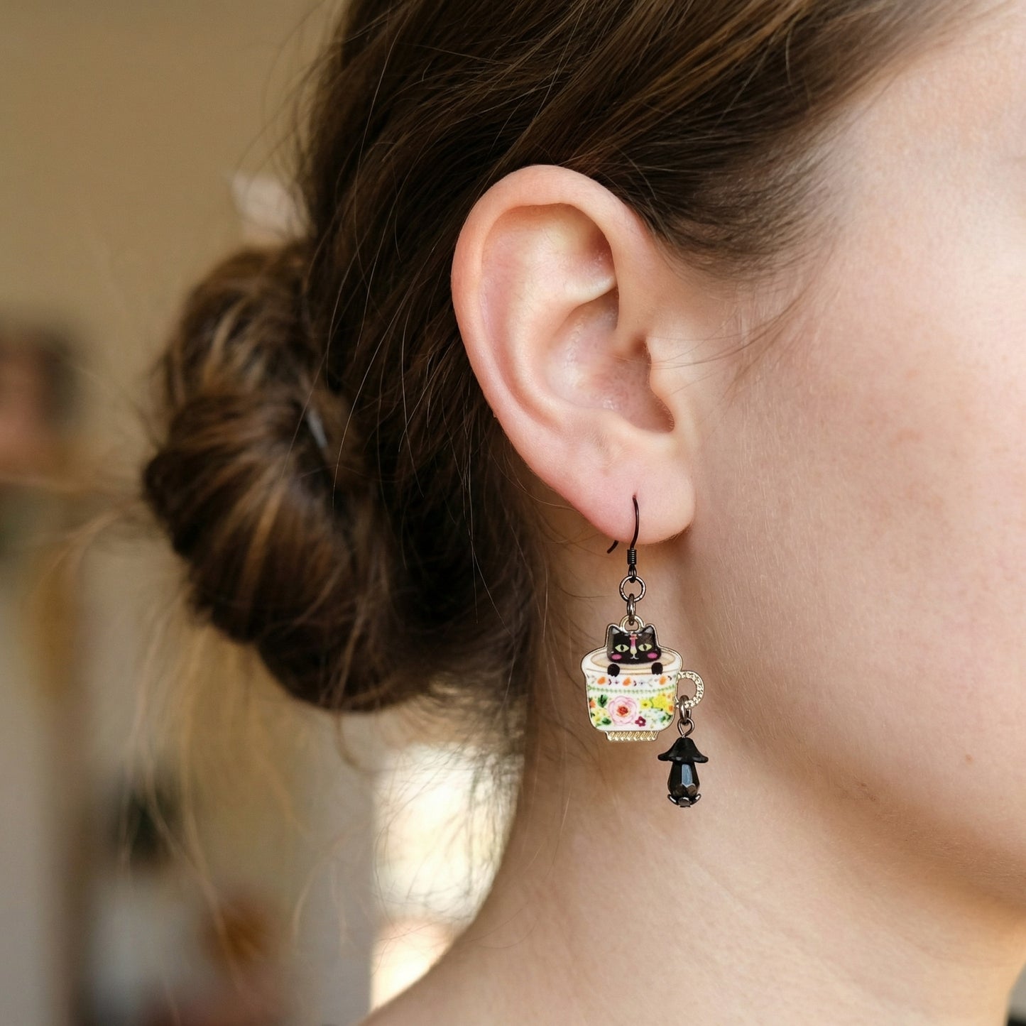 Close-up of a person wearing a decorative earring with a cat design.