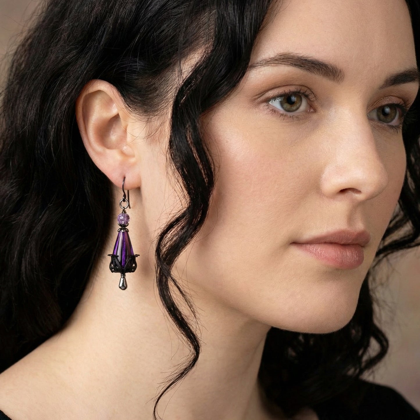 Close-up of a woman wearing purple earrings with a neutral background
