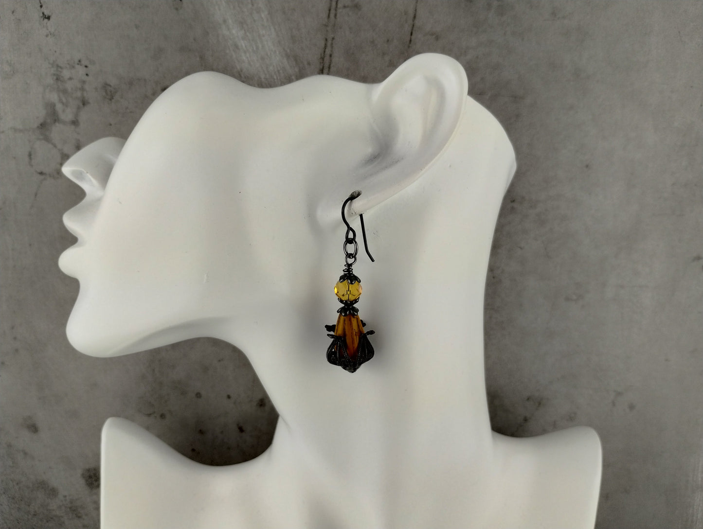 Earring displayed on a white mannequin ear against a gray background