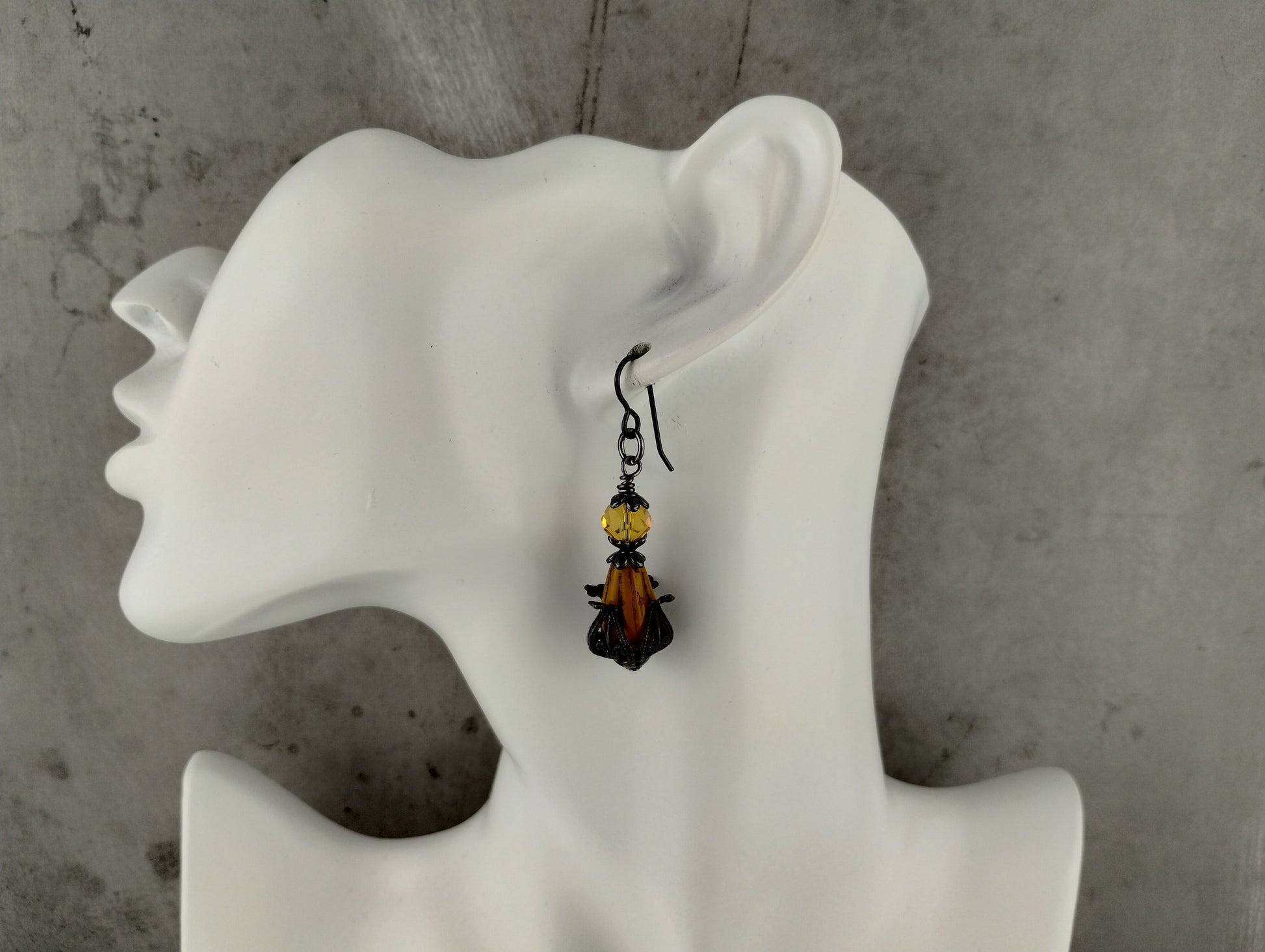 Earring displayed on a white mannequin ear against a gray background