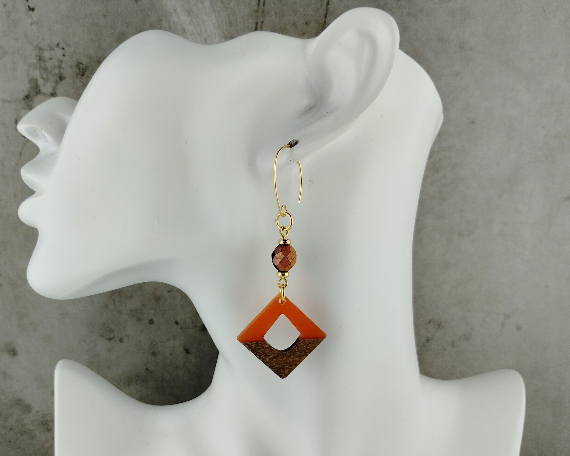 Earrings with geometric design on a white mannequin ear against a gray background