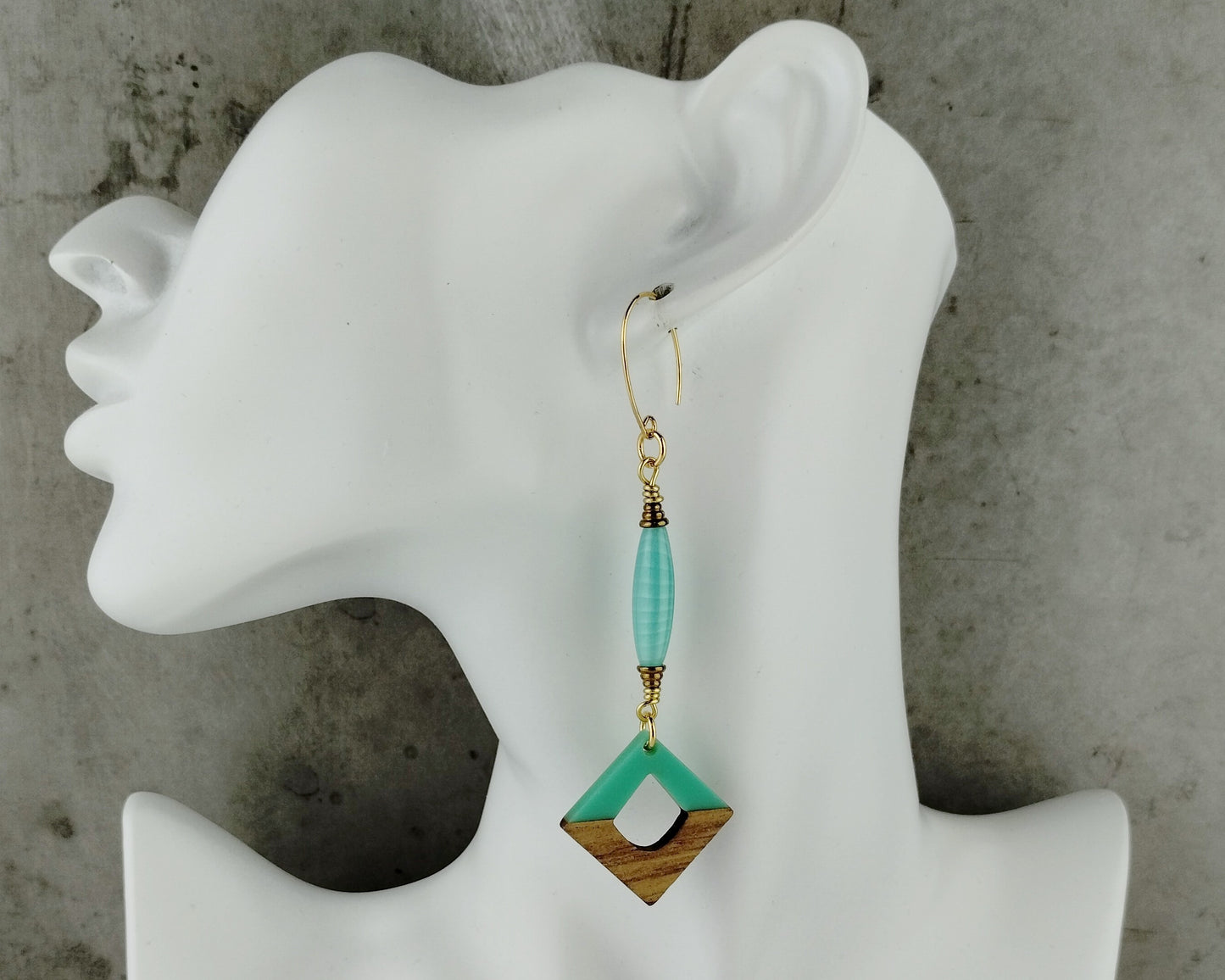 Earring displayed on a mannequin ear with a concrete background