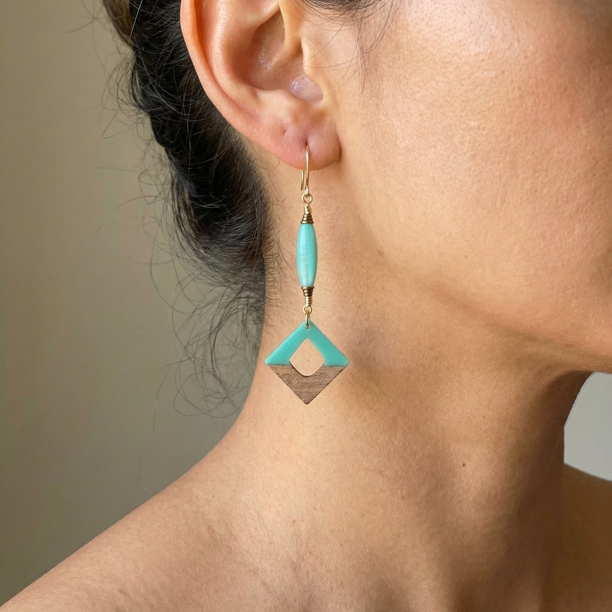 Close-up of a turquoise earring worn by a person against a neutral background