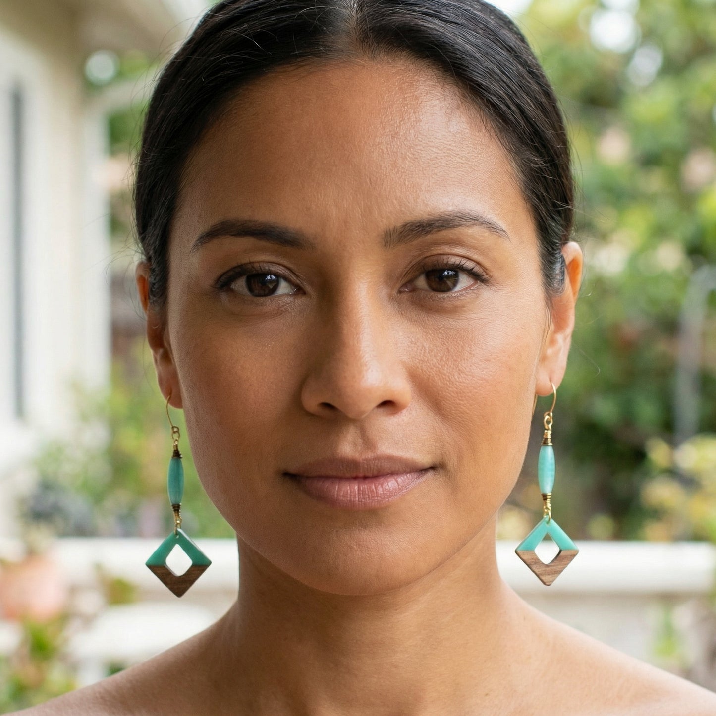 Woman wearing turquoise earrings with a blurred outdoor background