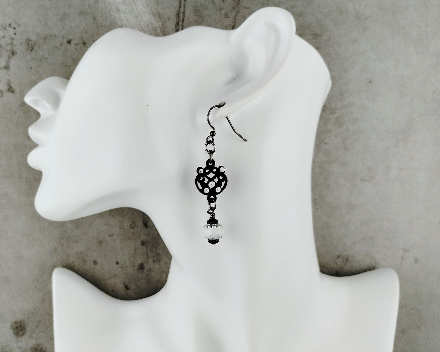 Black Filigree Earring on a white bust.
