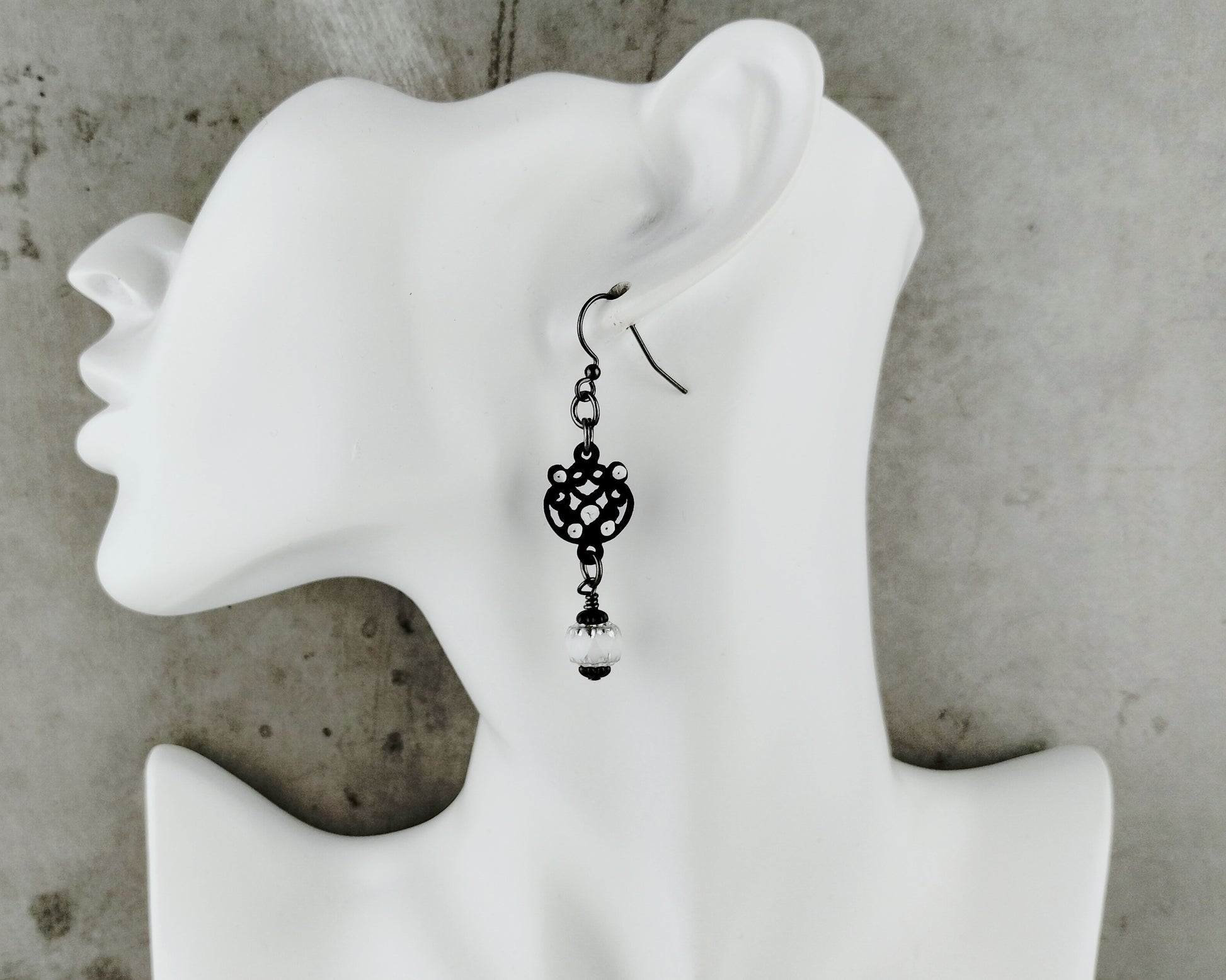 Black Filigree Earring on a white bust.
