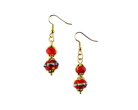 A pair of handmade dangle earrings featuring red glass beads with white and blue swirls, suspended from gold-tone wire hooks on a plain white background.