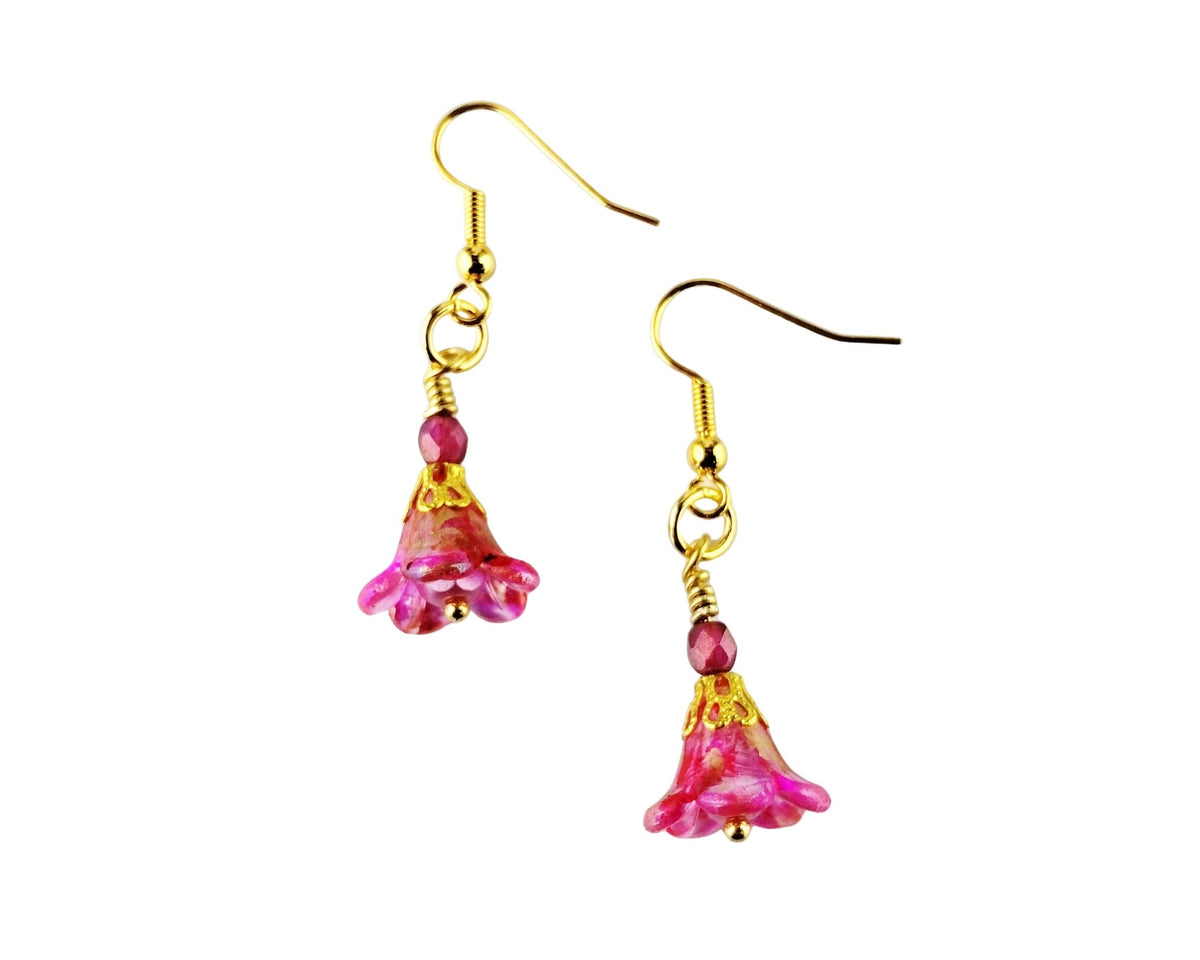 A pair of gold-tone dangle earrings with pink flower-shaped charms and small round pink beads, shown on a plain white background.