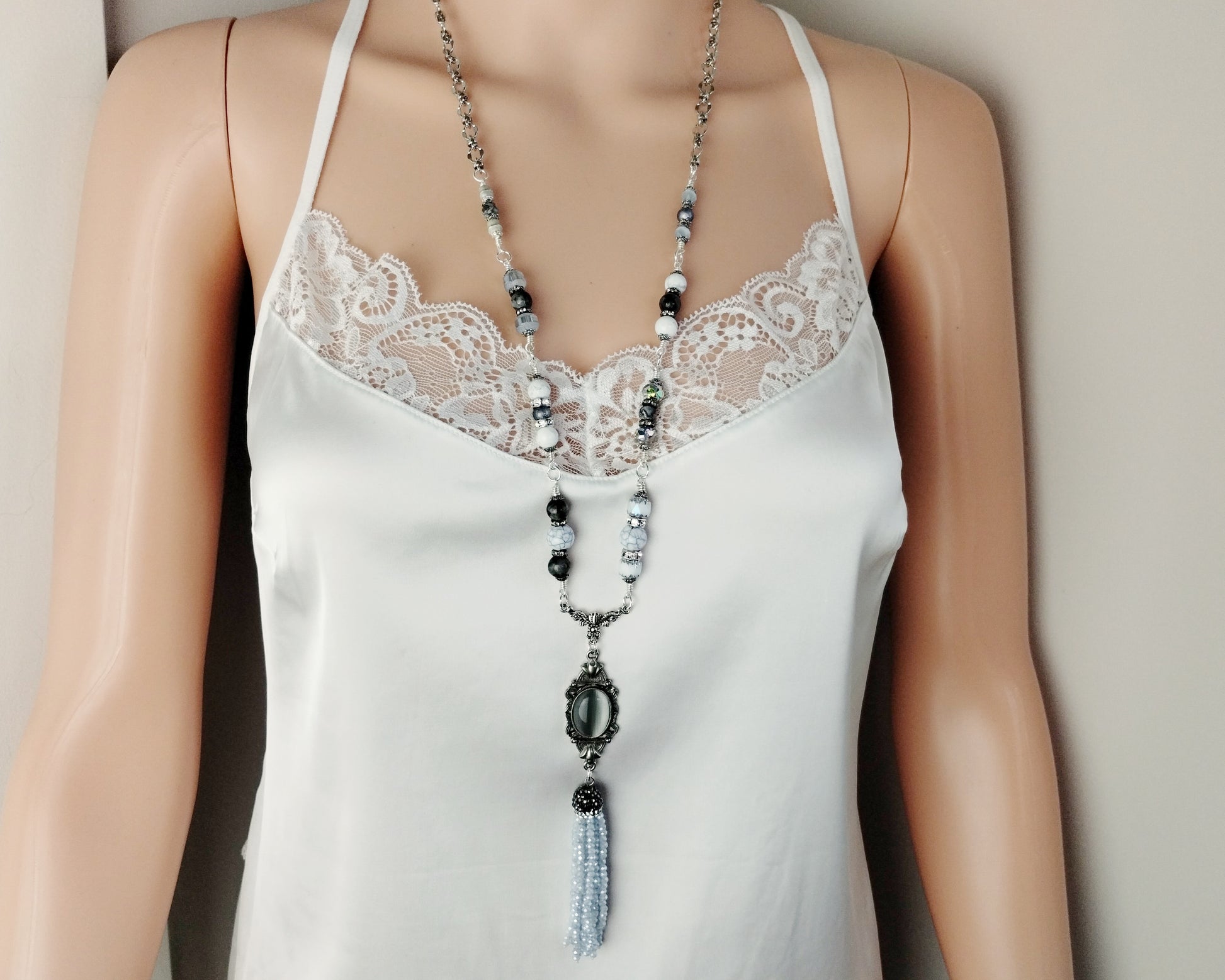 Long silver necklace with tassel drop and vintage-style gray cat’s eye centerpiece.