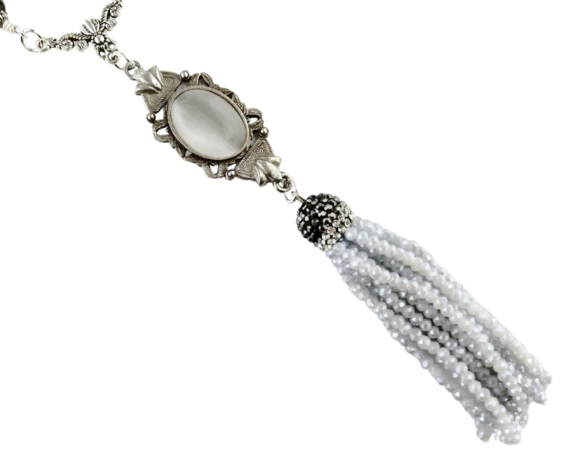 Close-up of white glass cat’s eye pendant with silver tassel and gray bead chain.