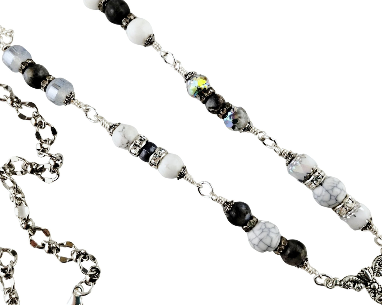 Close-up of white glass cat’s eye pendant with silver tassel and gray bead chain.