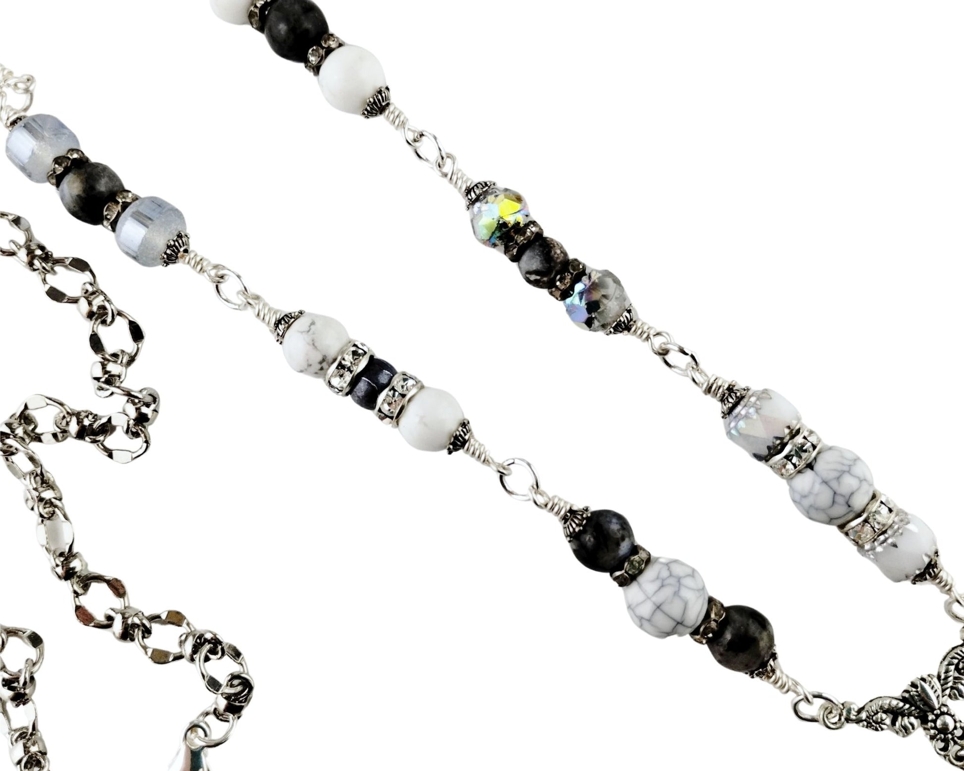 Close-up of white glass cat’s eye pendant with silver tassel and gray bead chain.