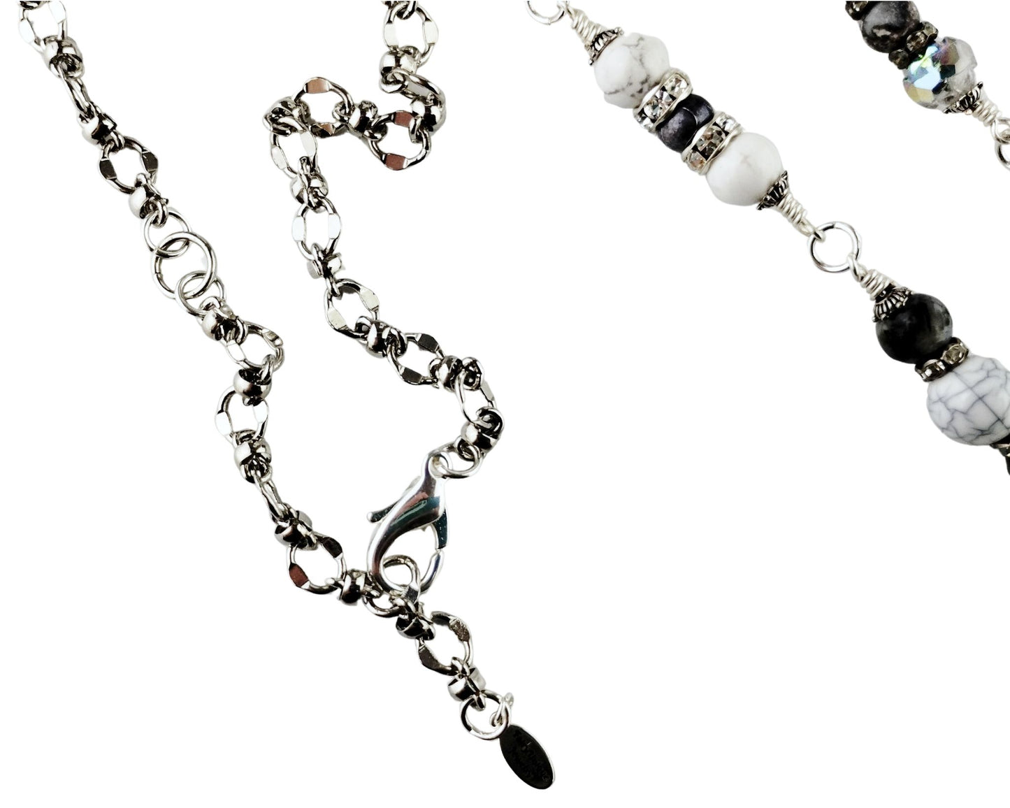 Close-up of white glass cat’s eye pendant with silver tassel and gray bead chain.