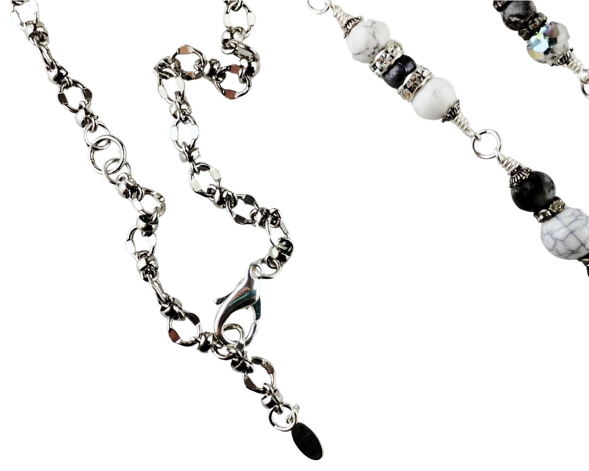 Close-up of white glass cat’s eye pendant with silver tassel and gray bead chain.