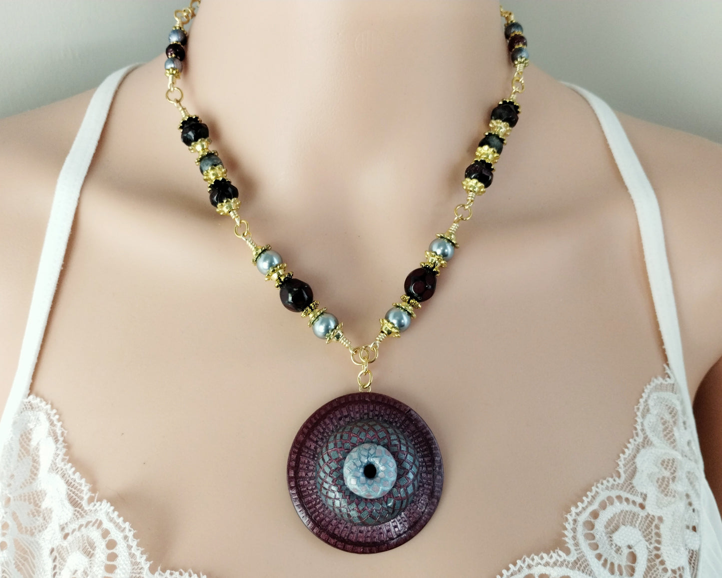 Adjustable artisan necklace with a burgundy and gray clay spiral pendant and pearl-accented strand.