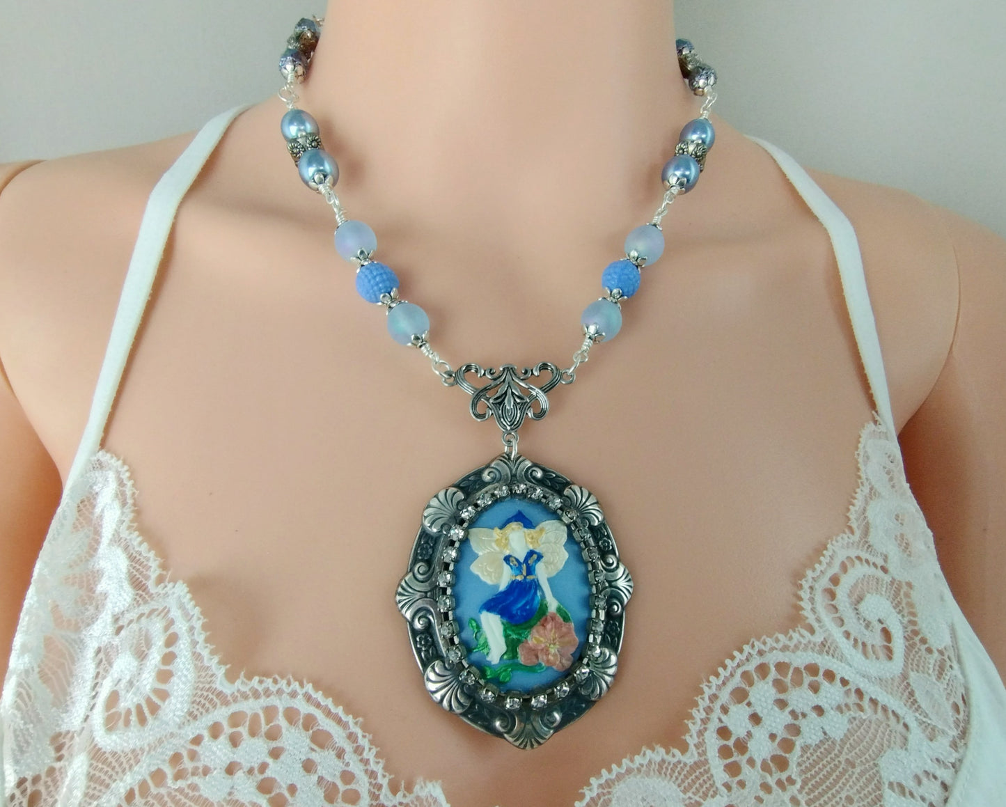 Whimsical fantasy pendant necklace with fairy artwork and silver-plated chain.