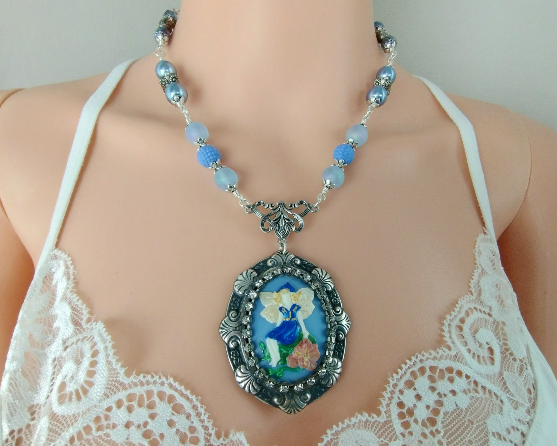 Whimsical fantasy pendant necklace with fairy artwork and silver-plated chain.