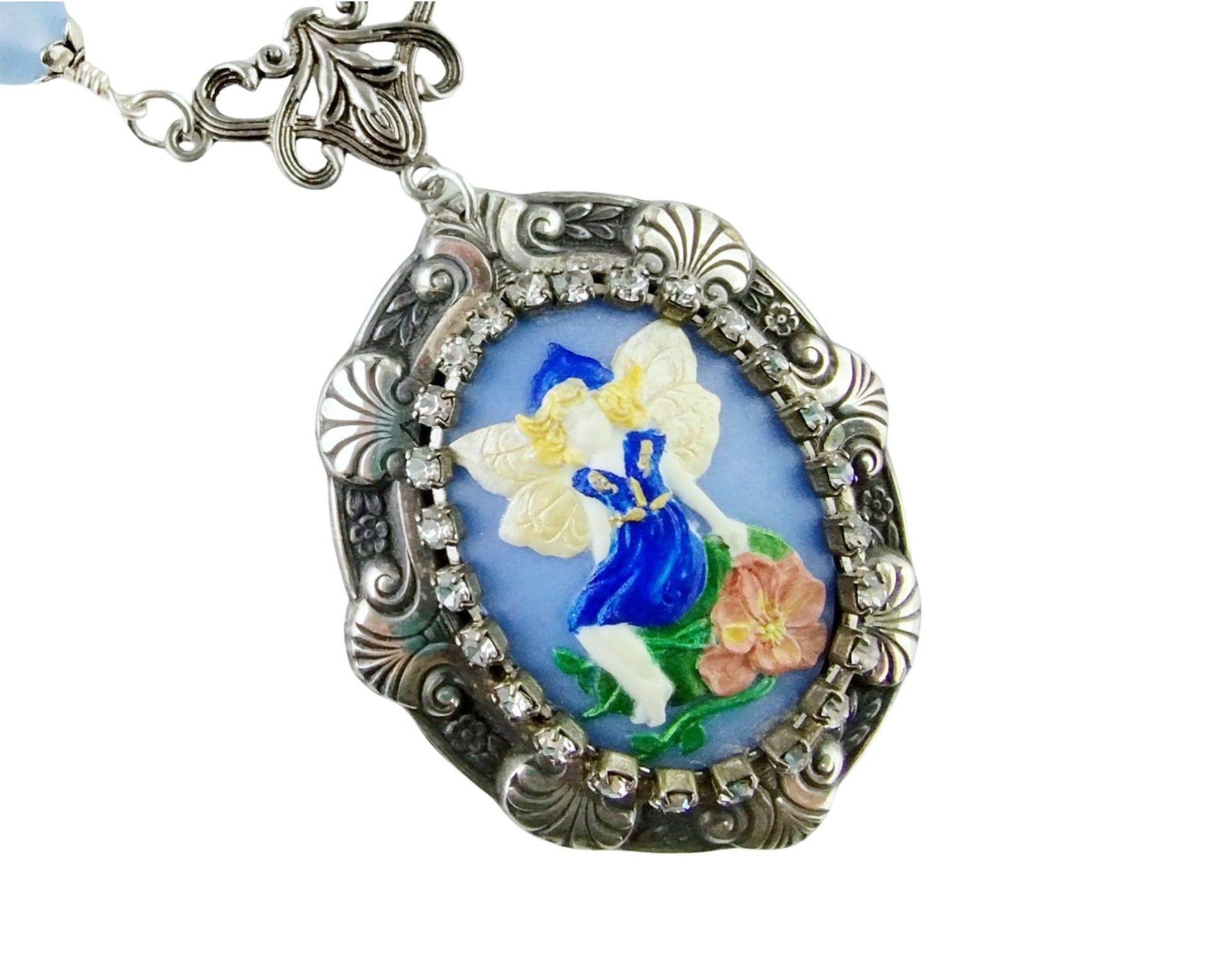 Close-up of handmade fairy cabochon pendant framed in silver with magical accents.