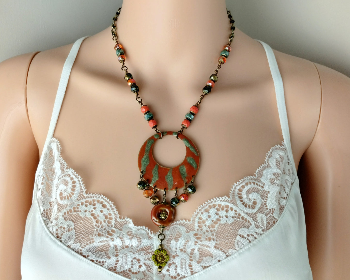 Necklace with a large circular pendant on a mannequin wearing a white lace top.