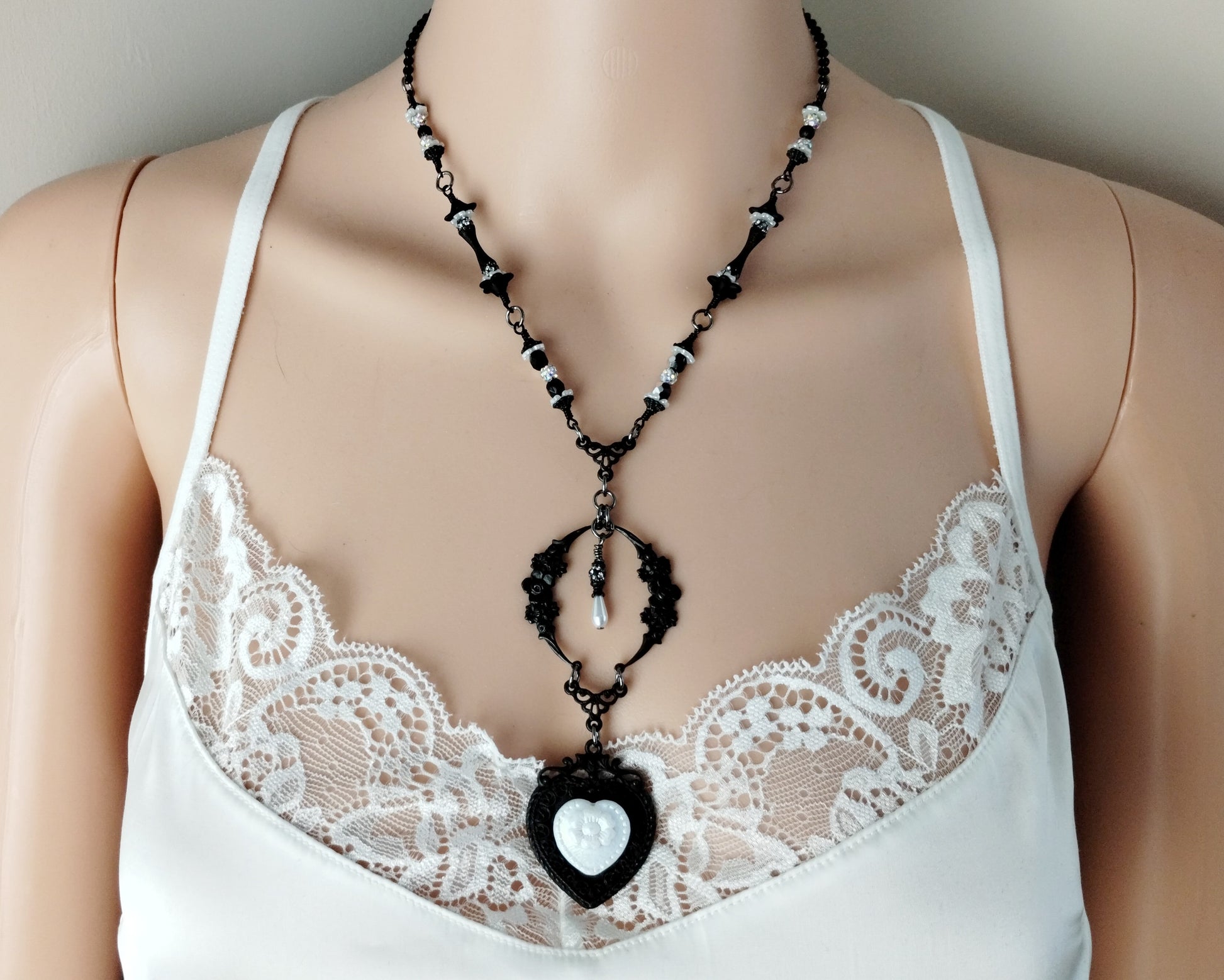 Mannequin wearing a white lace top with a black and white beaded necklace.