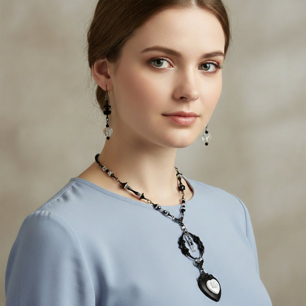 Woman wearing a black necklace and earrings against a neutral background